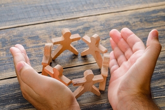 concepto-exito-empresarial-vista-superior-mesa-madera-manos-protegiendo-figuras-madera-personas.jpg